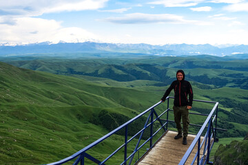 Fototapeta na wymiar A man on the background of the mountains and the Bermamyt plateau in Russia. June 2021