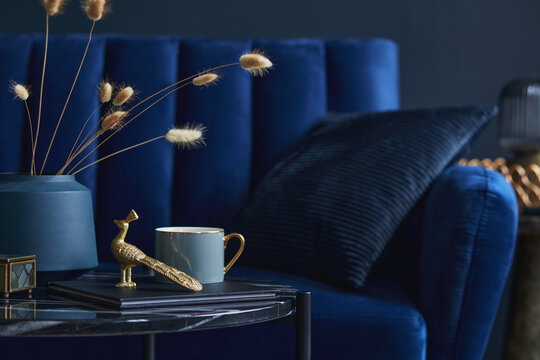 Stylish close up on the elegant details in the glamour living room interior. Golden peacock and creative personal accesories. Dark blue wall. Template. Copy space.. © FollowTheFlow