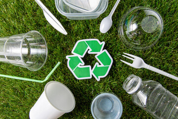environment, sustainability and ecology concept - close up of green recycling sign and plastic...