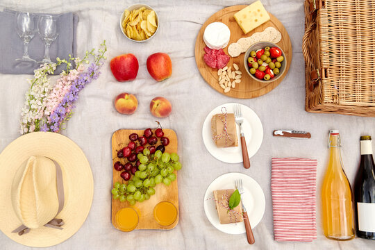 leisure and eating concept - close up of food, drinks and picnic basket on blanket