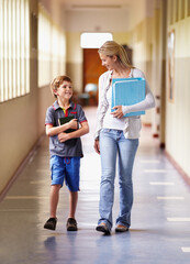 Everyone has that favorite teacher.... A teacher and young boy walking together down the corridor.