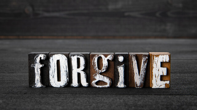 Forgive. Text from wooden blocks on a dark textured background