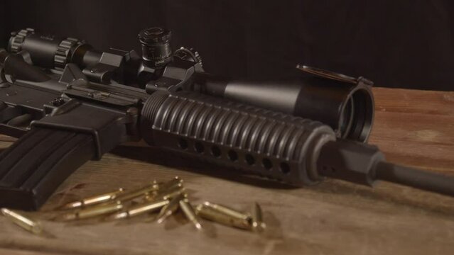 Dolly in of loaded AR-15 with ammo scattered around rifle