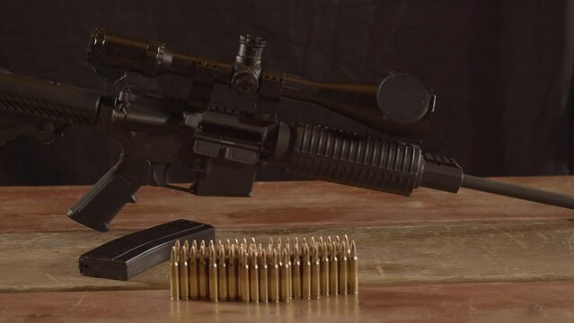 Dolly of AR-15 displayed on wooden surface with ammunition in foreground