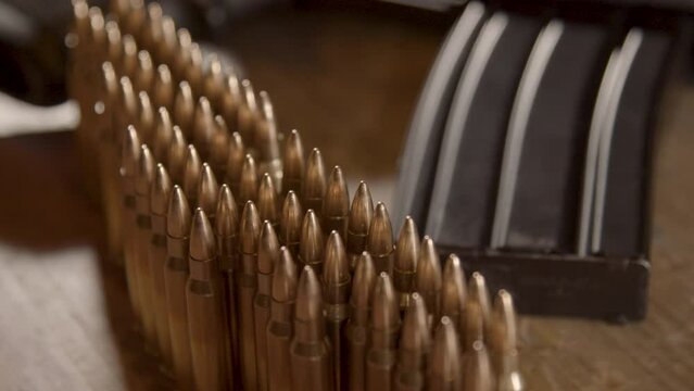 Macro dolly of bullets in 5.56 cartridges with an AR-15 in the background