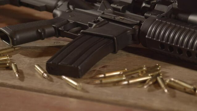 Dolly in over ammunition scattered in front of loaded AR-15