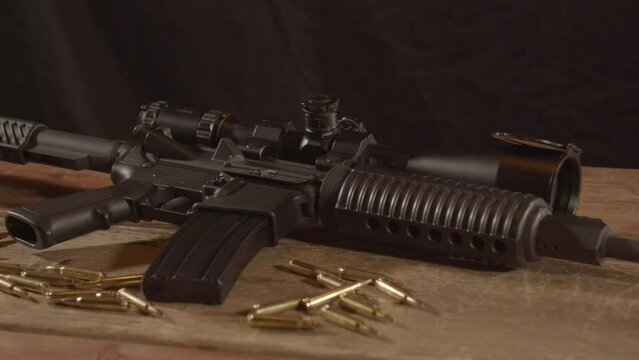 Wide dolly in of loaded AR-15 with live ammunition scattered around rifle