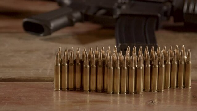 Dolly of .223 ammunition standing on wooden surface with an AR-15 in the background