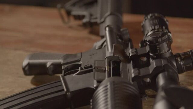 Close dolly over a loaded AR-15, ending on a close up of a barrel aiming towards camera