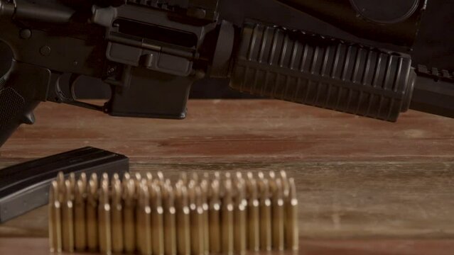 Dolly of AR-15 rifle, tilting down to ammo on a wooden surface