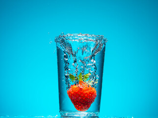 Strawberry falling into glass of water with splash 