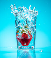 Strawberry falling into glass of water with splash 