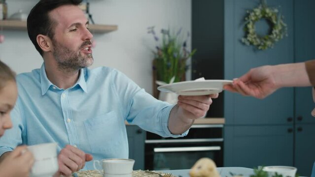 Unrecognizable woman cutting easter cake and passes a piece to the family in the background. Shot with RED helium camera in 8K.