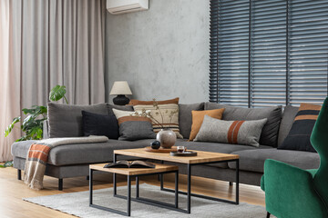 Stylish composition of elegant living room interior with grey corner sofa, coffee table and stylish personal accessories. Modern home decor. Panoramic windows. Template.