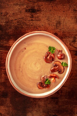 Mushroom cream soup, shot from above on a dark rustic wooden table, garnished with parsley