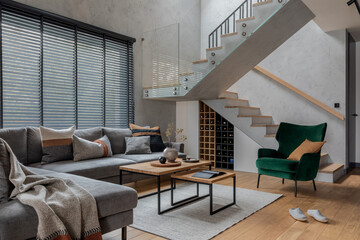 Modern living room interior design. Grey corner sofa, velvet armchair, coffee table and minimalist...