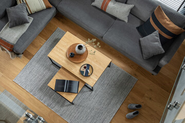 Stylish top view composition of living room interior with corner grey sofa, coffee table, carpet...