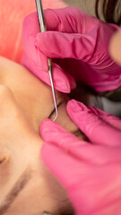 Vertical of woman on the procedure for eyelash extensions, lamination in beauty salon. Cosmetologist applying glue on woman's lashes. Close-up of girl face during lash lift laminating botox set. 