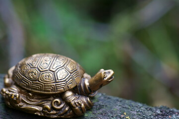 Naklejka premium Turtle figurine close-up on a background of green leaves.