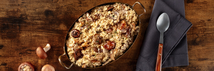 Risotto ai funghi, mushroom rice panorama, top shot on a dark wooden background with a place for text