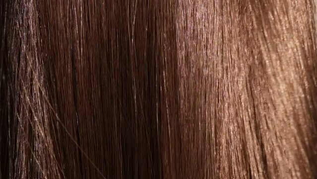 Beautiful healthy brown Hair. A closeup view of a bunch of shiny straight brown hair in a wavy style. slow motion smooth flowing hair fluttering