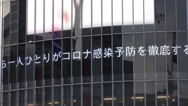 SHIBUYA. TOKYO, JAPAN - 29 FEB 2022 : Message of countermeasures against the Coronavirus (COVID-19) on the screen at Shibuya Scramble Crossing area. Wear mask, wash hand and avoid crowd.