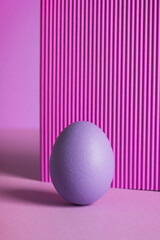 Easter egg still life on purple background. Minimal composition. Close up, vertical