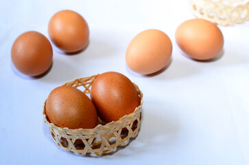 fresh chicken eggs in a small basket on a white background