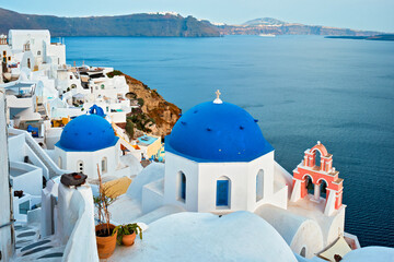 Fototapeta na wymiar Famous view from viewpoint of Santorini Oia village with blue dome of whitewashed greek orthodox Christian church of traditional greek architecture. Oia town, Santorini island, Greece