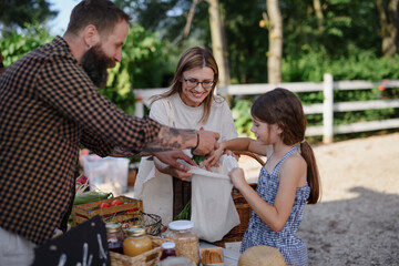 Happy little girl with mother buying vegetables outdoors at local family farmers market.