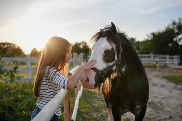 Little girl hugging horse outdoors at community farm.