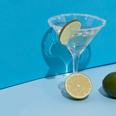 Martini glass with vermouth, sugar and lime slice. Flat lay.Turquoise and light blue background. Creative minimal concept.