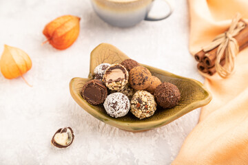 Chocolate truffle candies with cup of coffee on a gray concrete background. side view, close up, selective focus.