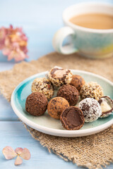 Chocolate truffle candies with cup of coffee on a blue wooden background. side view, close up, selective focus.