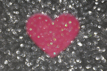 Gray glitter background, pink glitter heart in the middle
