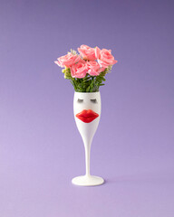 Creative layout made of white wineglass with lips eyelashes and roses. Minimal spring flower concept.
