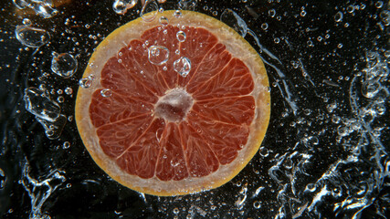 Fresh grapefruit falling into water, freeze motion, underwater view.