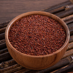Organic red quinoa in a bowl on wooden table background.