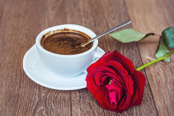 Coffee cup and  red rose on a wooden background 