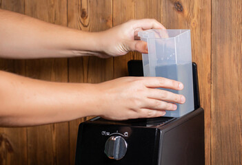 A man inserts a container of water into a coffee maker to make coffee, close-up