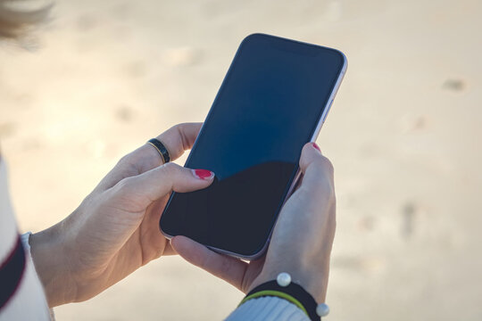 Woman With Ring, Bracelet And Painted Nails Holding A Mobile Phone With Her Hands While Writing A Message And Receiving Mail.