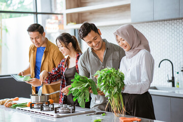 Good friends laughing and talking while preparing meals at table for cooking in kitchen