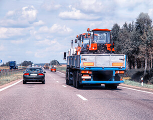 Transporting new tractors in a truck trailer on the road. Oversized cargo transportation, industry. Copy space for text