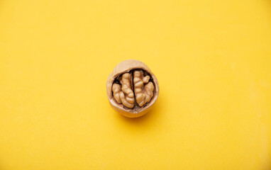 Walnut with broken shells on a yellow background, close-up. Walnut resembling a human brain