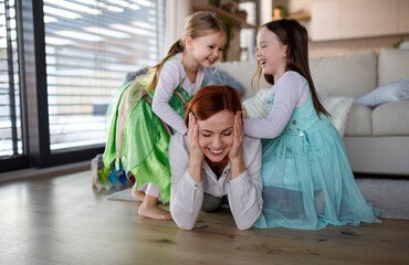 Happy mother having fun with little daughters in princess costumes at home. © Halfpoint