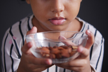 kid hand holding a bowl of almond on black 