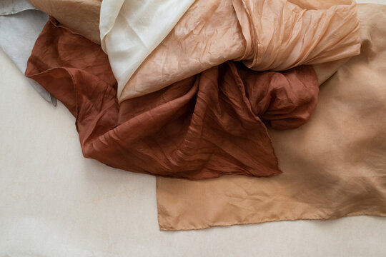 hand dyed clothes in warm natural tones on a bright background - text space -
slow fashion concept 