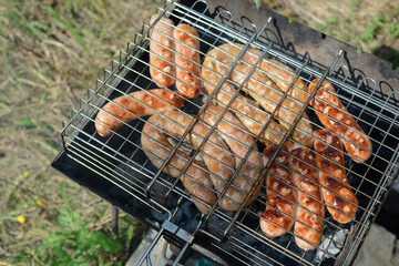 Fragrant sausages are cooked on the grill.