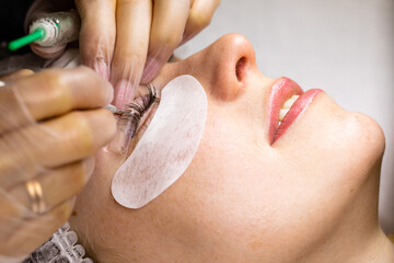 Female face under procedure of eyelashes lamination in beauty salon