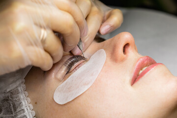 Female face under procedure of eyelashes lamination in beauty salon